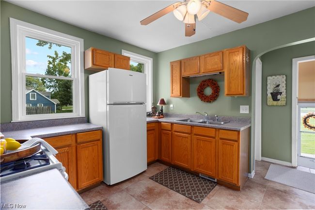 Kitchen featuring white refrigerator, tile floors, ceiling fan, and brown cabinets | Image 6