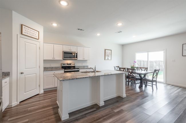 Kitchen with electric range oven, stainless steel microwave, a sink, dark wood finished floors, and light stone countertops | Image 9