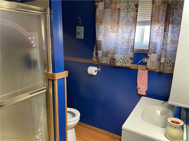 Bathroom featuring toilet, hardwood / wood-style floors, vanity, and a shower with door | Image 15
