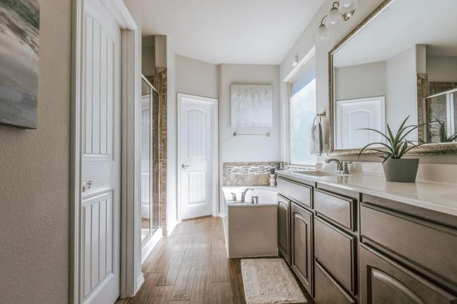 Bathroom featuring a stall shower, a garden tub, vanity, and wood finished floors | Image 26