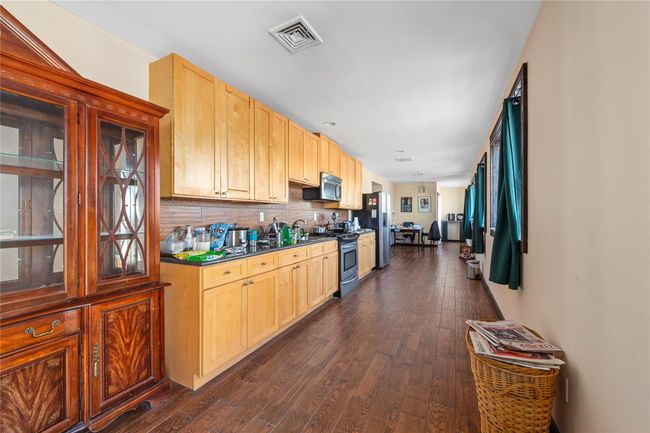 Kitchen with appliances with stainless steel finishes, dark hardwood / wood-style floors, backsplash, and light brown cabinetry | Image 24