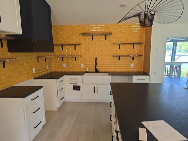 Kitchen featuring open shelves, dark countertops, white cabinetry, exhaust hood, and light wood finished floors | Image 6