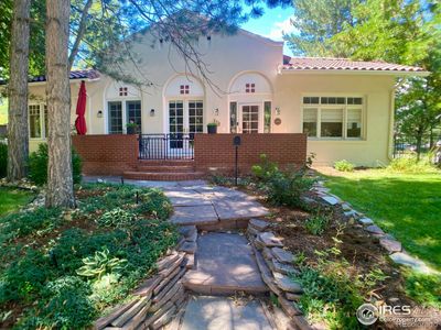 Mature gardens and trees surround the front walk. | Image 2