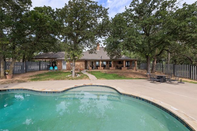 View of swimming pool featuring a patio area, a fenced in pool, and fence | Image 23