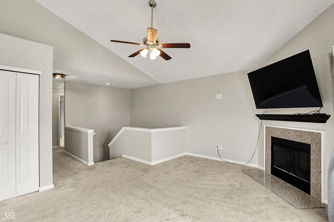 unfurnished living room featuring carpet, ceiling fan, a fireplace, and high vaulted ceiling | Image 11