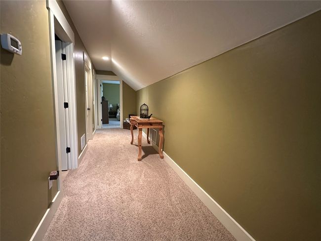 Hallway featuring light carpet and lofted ceiling | Image 22