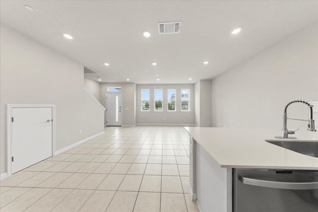 Kitchen with stainless steel dishwasher, a sink, baseboards, light tile patterned flooring, and recessed lighting | Image 8