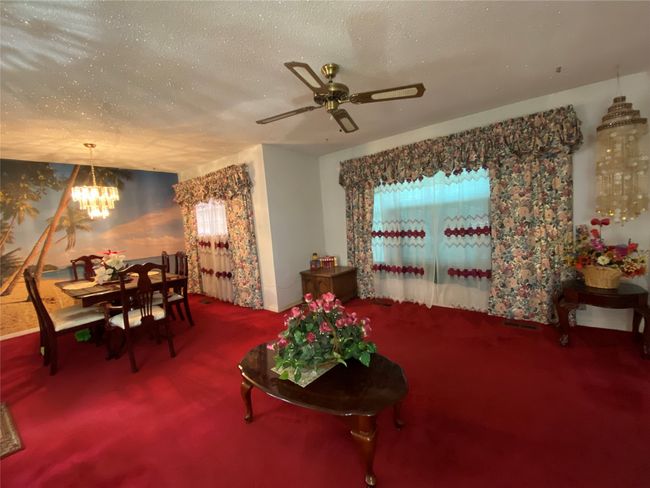 Carpeted living area with a chandelier, a textured ceiling, and ceiling fan | Image 8