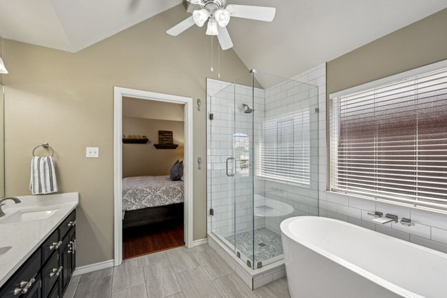 Ensuite bathroom with a ceiling fan, a freestanding tub, double vanity, a shower stall, and vaulted ceiling | Image 23