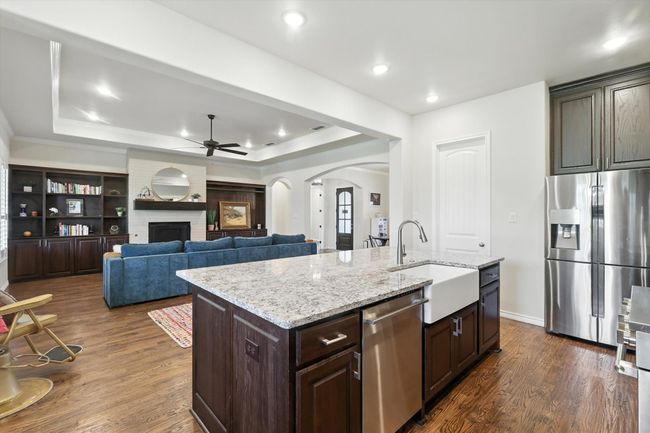 Kitchen featuring appliances with stainless steel finishes, arched walkways, ceiling fan, a tray ceiling, and a brick fireplace | Image 17