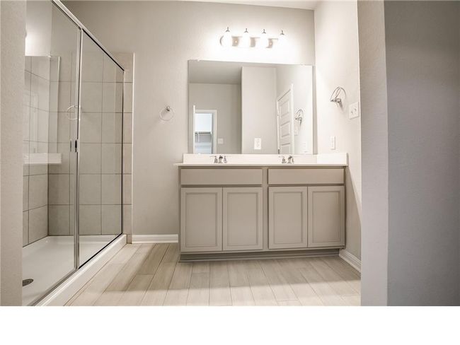 Bathroom featuring tiled shower, double vanity, and wood finished floors | Image 16