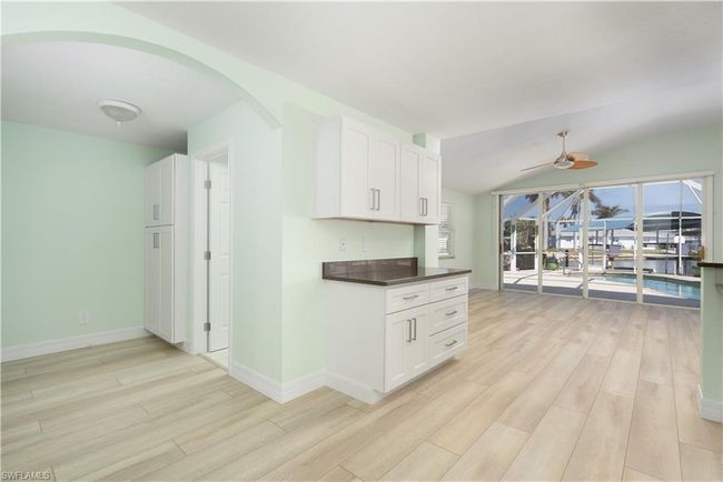Kitchen featuring white cabinets, arched walkways, ceiling fan, and light wood-style floors | Image 9