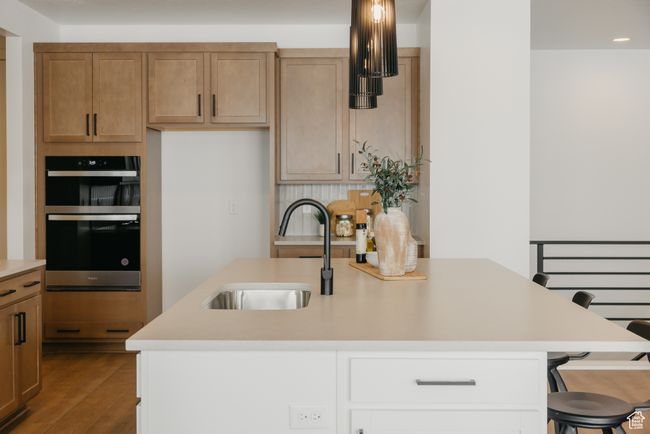 Kitchen with double oven, a sink, light countertops, dark wood-type flooring, and a breakfast bar area | Image 18