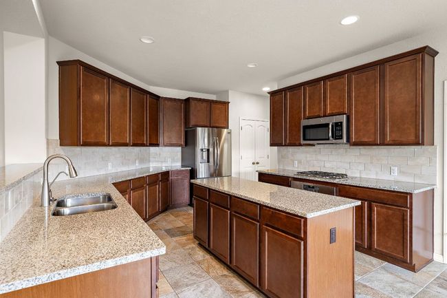 Kitchen with a kitchen island, appliances with stainless steel finishes, decorative backsplash, and a sink | Image 10