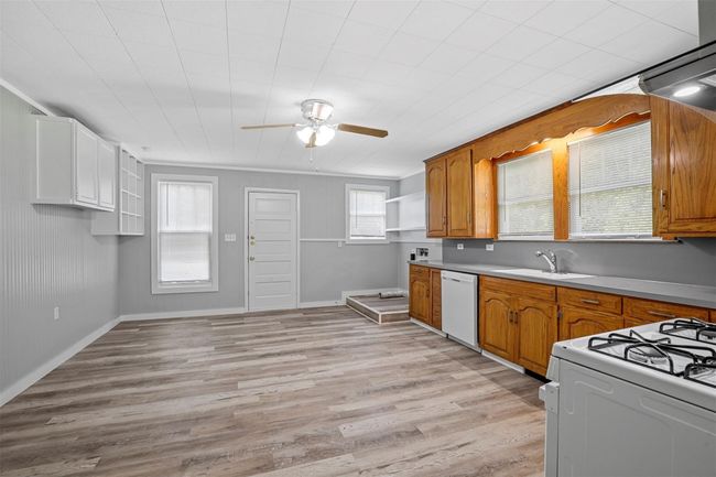 Kitchen featuring white appliances, a ceiling fan, light wood finished floors, and brown cabinets | Image 7
