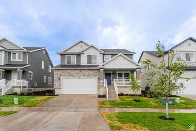 View of front of house featuring a front lawn, covered porch, and a garage | Image 1