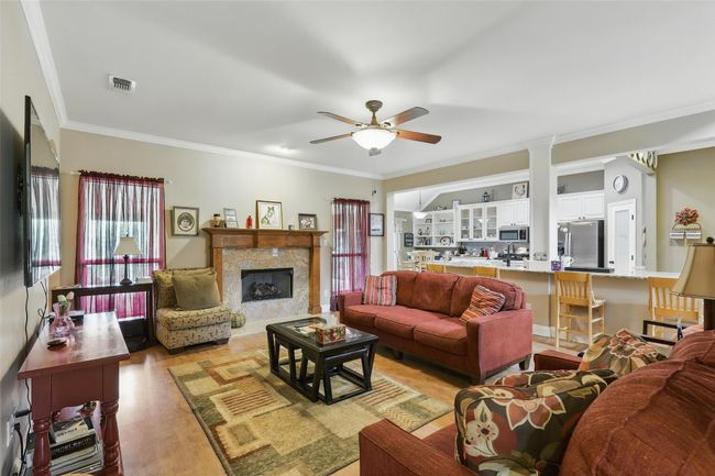 Living room with ornamental molding, ceiling fan, light wood-type flooring, and a fireplace | Image 16