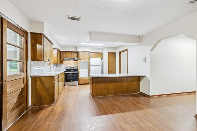 Kitchen area complete with breakfast bar, granite, updated lighting, updated electric range, undermount ss kitchen sink and pantry. | Image 11