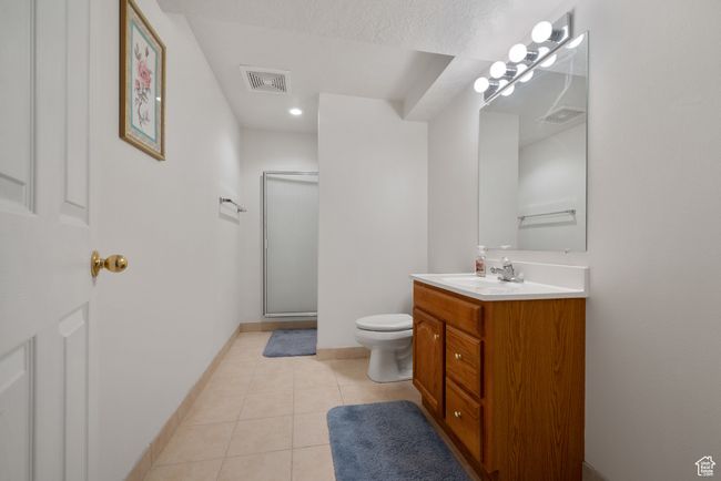 Bathroom featuring vanity, a stall shower, tile patterned floors, and recessed lighting | Image 26