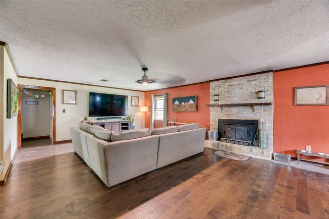 Living area with crown molding, a fireplace, hardwood / wood-style flooring, and a textured ceiling | Image 9