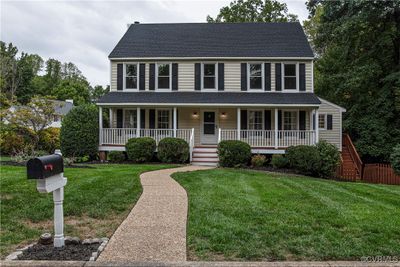 Colonial inspired home with covered porch and a front yard | Image 1