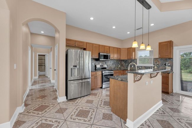 Kitchen featuring stainless steel appliances, backsplash, arched walkways, light tile patterned floors, and recessed lighting | Image 14