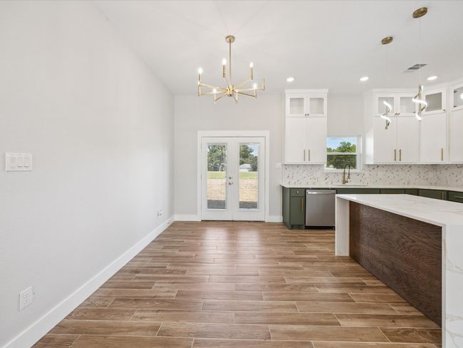 Kitchen featuring dishwasher, a chandelier, light wood-style flooring, backsplash, and white cabinetry | Image 10