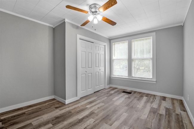 Unfurnished bedroom featuring ornamental molding, a closet, wood finished floors, and ceiling fan | Image 9