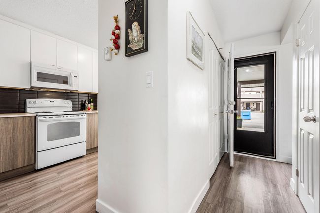 Kitchen featuring white appliances, light wood-style flooring, decorative backsplash, white cabinets, and modern cabinets | Image 7
