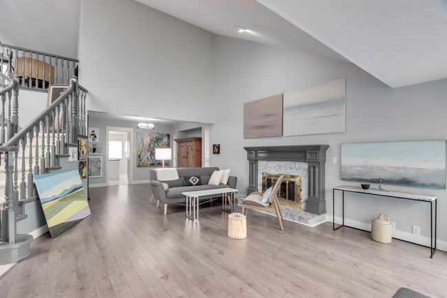 Living area with wood finished floors, stairs, a fireplace, and high vaulted ceiling | Image 4