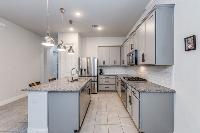 Kitchen with light tile patterned floors, gray cabinets, appliances with stainless steel finishes, and a sink | Image 10
