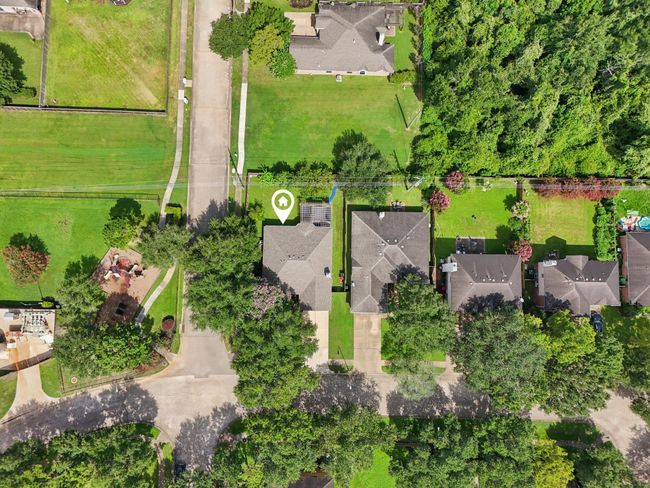 This aerial photo showcases a suburban neighborhood with tree-lined streets and well-maintained homes. The highlighted property features a spacious backyard and is adjacent to a greenbelt, offering privacy and scenic views. Perfect for buyers seeking a serene environment with ample outdoor space. | Image 27