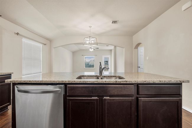Kitchen featuring dishwasher, ceiling fan, dark wood-style floors, arched walkways, and dark brown cabinetry | Image 11