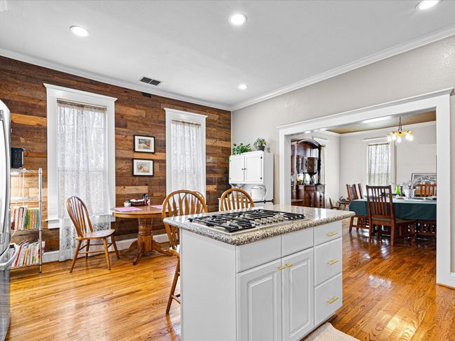 Kitchen with white cabinets, ornamental molding, light wood finished floors, and stainless steel gas cooktop | Image 8