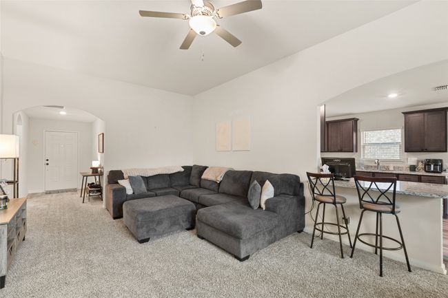 Living area with arched walkways, light colored carpet, and ceiling fan | Image 7
