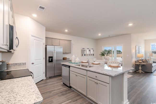 Kitchen featuring stainless steel appliances, gray cabinetry, wood finished floors, open floor plan, and a center island with sink | Image 6