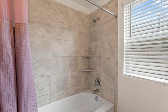 Hall bath features ceramic tile surround, shower/tub combo and a window to provide lots of natural light. | Image 25