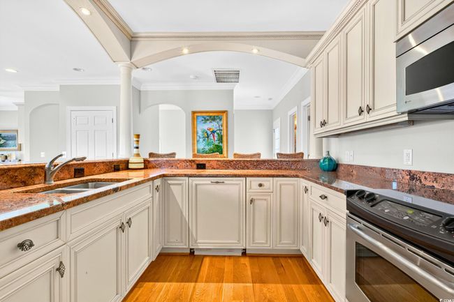 Kitchen featuring stainless steel appliances, ornamental molding, dark stone countertops, light wood-style flooring, and recessed lighting | Image 12