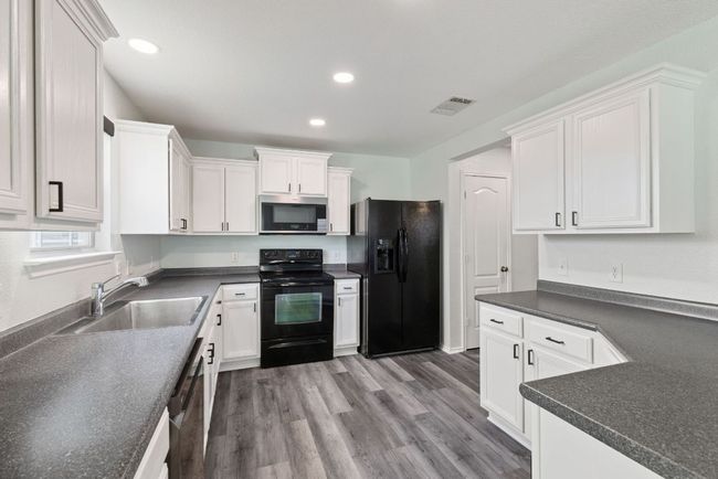 Kitchen with black appliances, new sink, white cabinets, dark countertops, and recessed lighting | Image 10