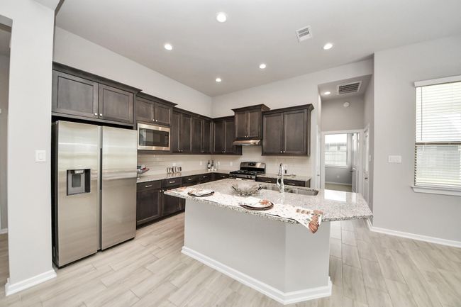 Chef’s kitchen with granite countertops, oversized island, and stainless-steel appliances | Image 16