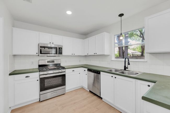 Kitchen featuring backsplash, appliances with stainless steel finishes, a sink, and hanging light fixtures | Image 10