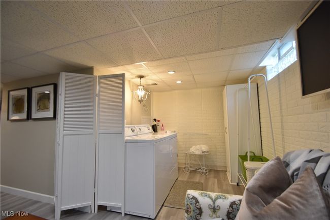 Washroom with wood finished floors, brick wall, and washing machine and clothes dryer | Image 28
