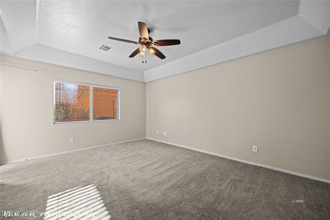 Empty room featuring carpet flooring, baseboards, a textured ceiling, ceiling fan, and visible vents | Image 25
