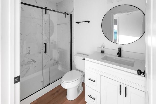 Full bath with a marble finish shower, vanity, toilet, and wood finished floors | Image 11