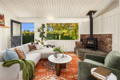 The cozy wood stove lends charm and warmth to this window-filled home while the farmhouse door leads you to the back porch with room for outdoor dining | Image 3