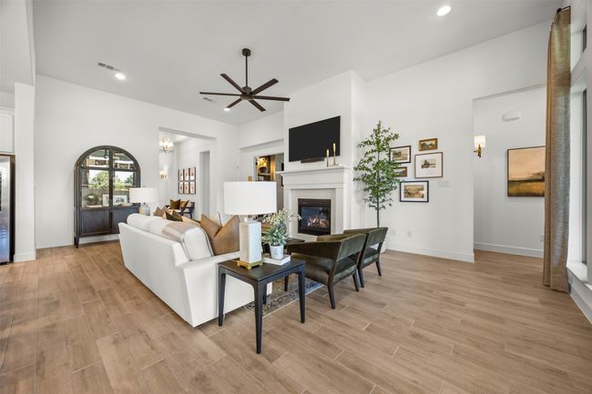 Living area with light wood-style floors, a ceiling fan, a glass covered fireplace, and recessed lighting | Image 7