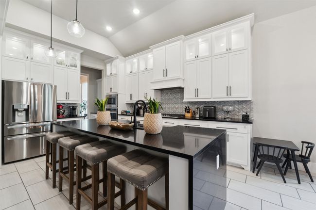 Kitchen featuring appliances with stainless steel finishes, dark countertops, tasteful backsplash, vaulted ceiling, and decorative light fixtures | Image 13