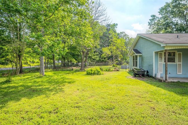 Spacious side yard with lush greenery and mature trees, offering privacy and a serene outdoor retreat. | Image 4