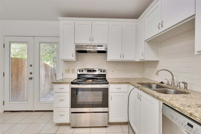 Kitchen with stainless steel electric range oven, french doors, white cabinetry, and dishwasher | Image 13