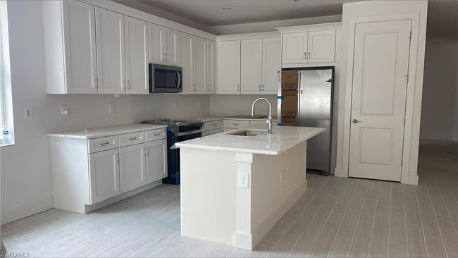 Chef's kitchen with lovely quartz countertops, soft-close cabinets and drawers, Whirlpool appliances including range microwave, gas oven, 36" side-by-side refrigerator, and dishwasher | Image 5